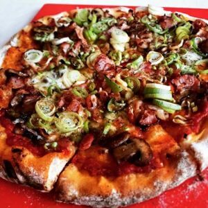 pizza med porre og bacon på bord